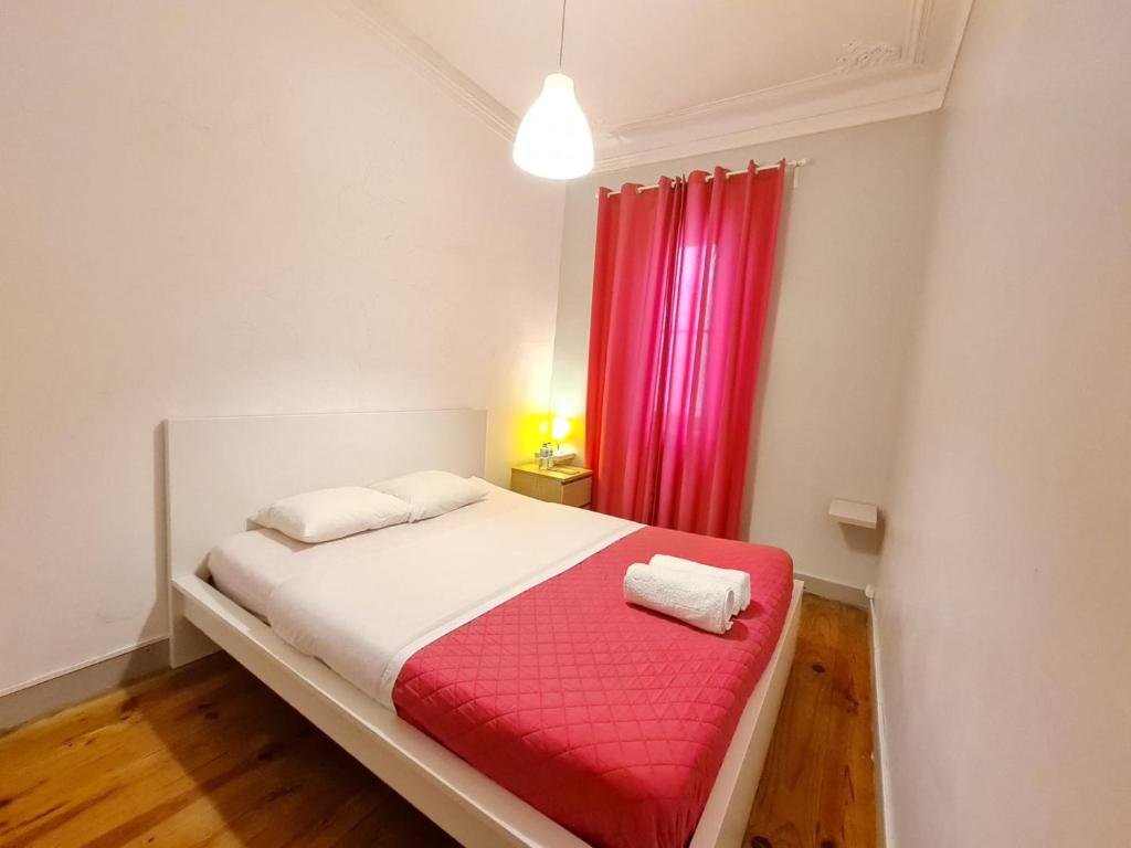 1 dormitorio con 1 cama con cortina roja en Shangri-La Hostel Anjos, en Lisboa