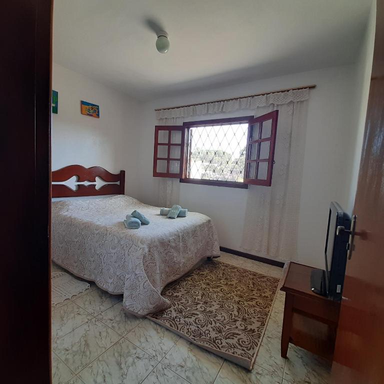 a bedroom with a bed and a window and a television at Casa Quintanilha in Campos do Jordão