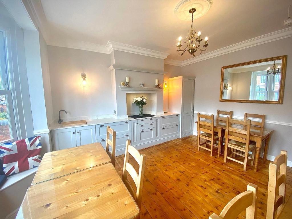a dining room with a wooden table and a kitchen at Quilt and Croissants Guest House in Stratford-upon-Avon