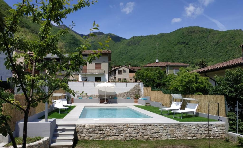 una piscina en un patio con sillas y una casa en Prosecco hills, 1 hour from Venice, swimming pool, ground floor, en Miane