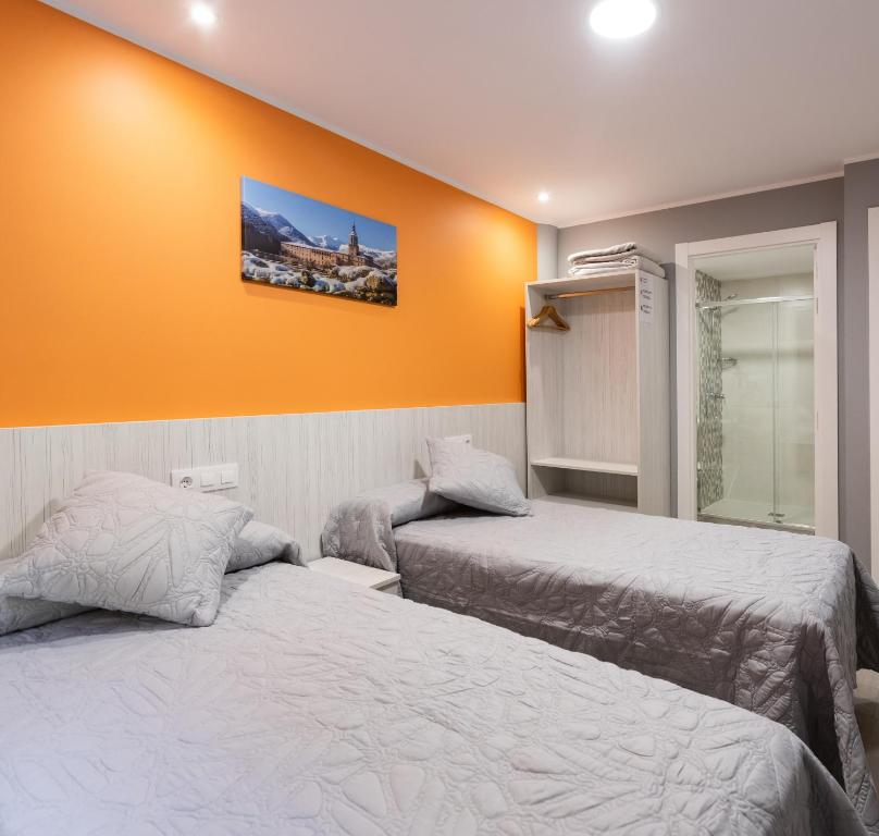 two beds in a room with an orange wall at Pensión San Lorenzo 2 in Nájera