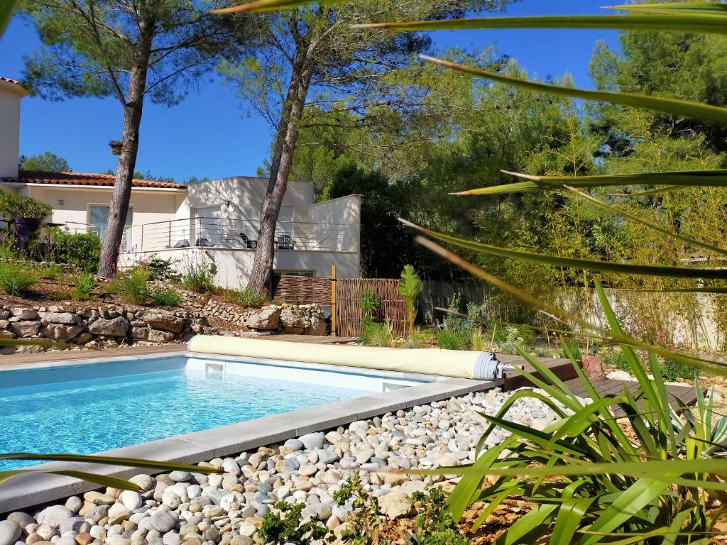 a swimming pool in a yard with rocks and trees at Studio d'Hôtes les Libellules in Castelnau-le-Lez