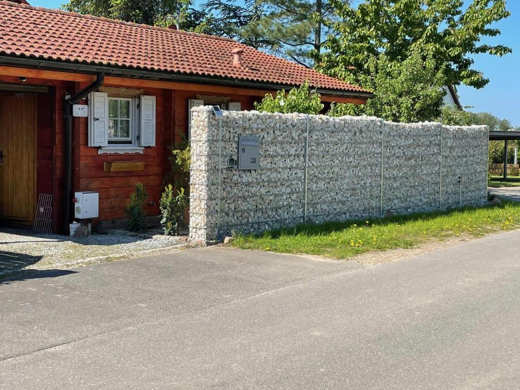 a house with a stone wall next to a fence at Ferienhaus " Uns Hüsung" in Rerik