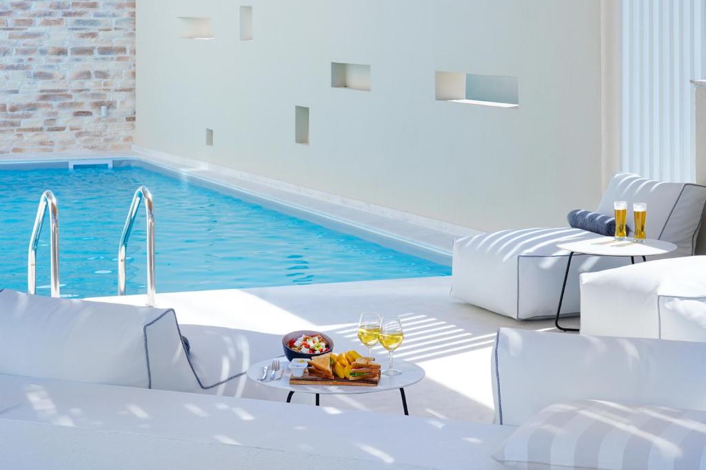 una piscina con muebles blancos y una mesa con copas de vino en Aelia Villa, en Limenas