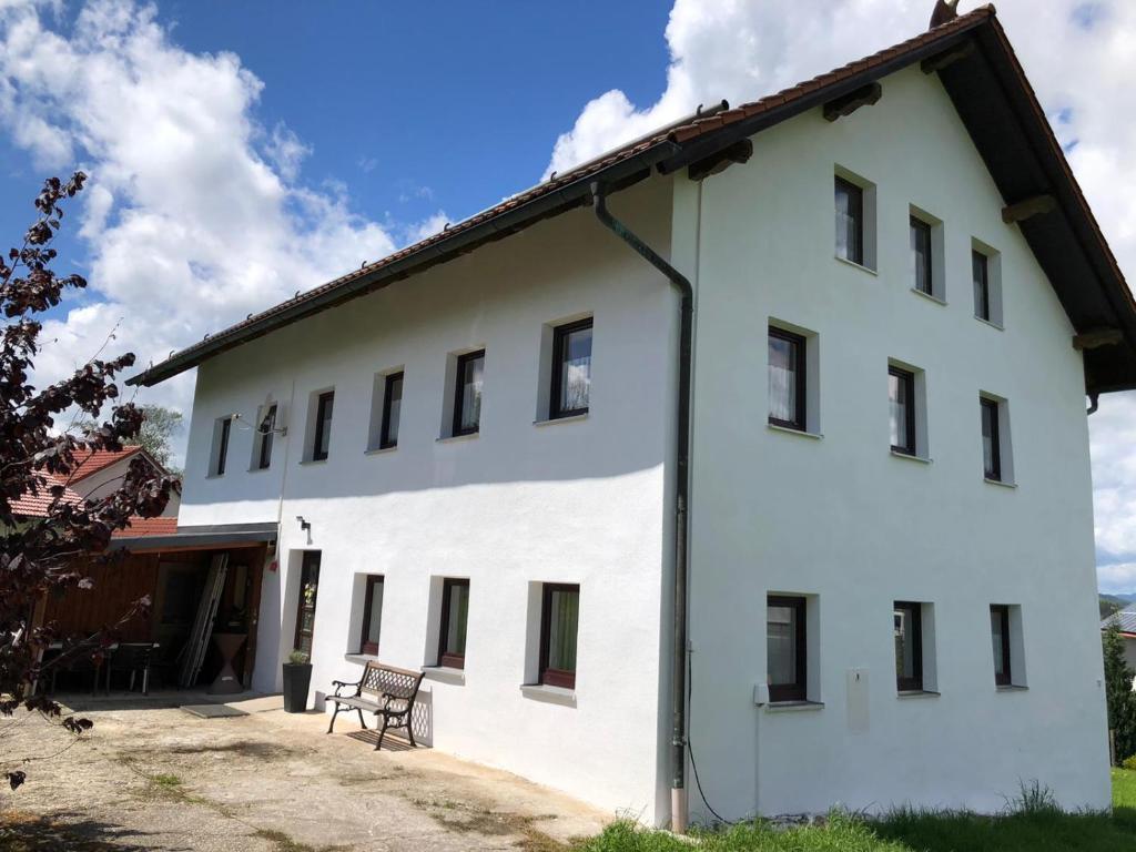 ein weißes Gebäude mit einer Bank davor in der Unterkunft Bauernhaus Auberg ganzes Haus in Hutthurm