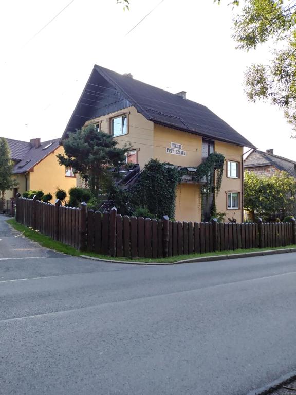 uma casa amarela com uma cerca ao lado de uma rua em Noclegi Przy Szlaku Agroturystyka em Żabnica