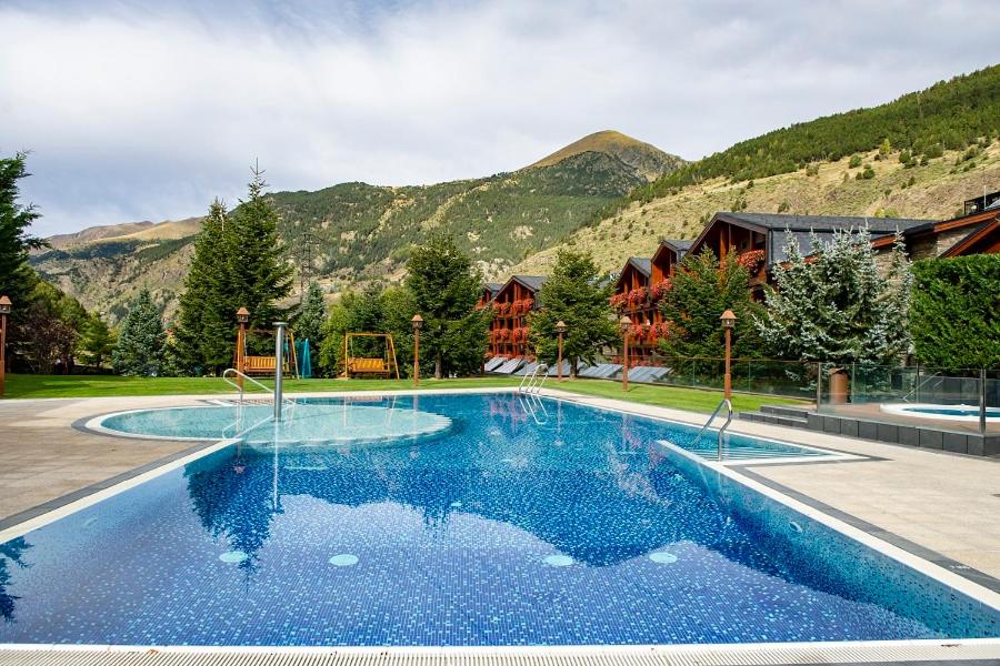 a large swimming pool with mountains in the background at Hotel Nordic in El Tarter