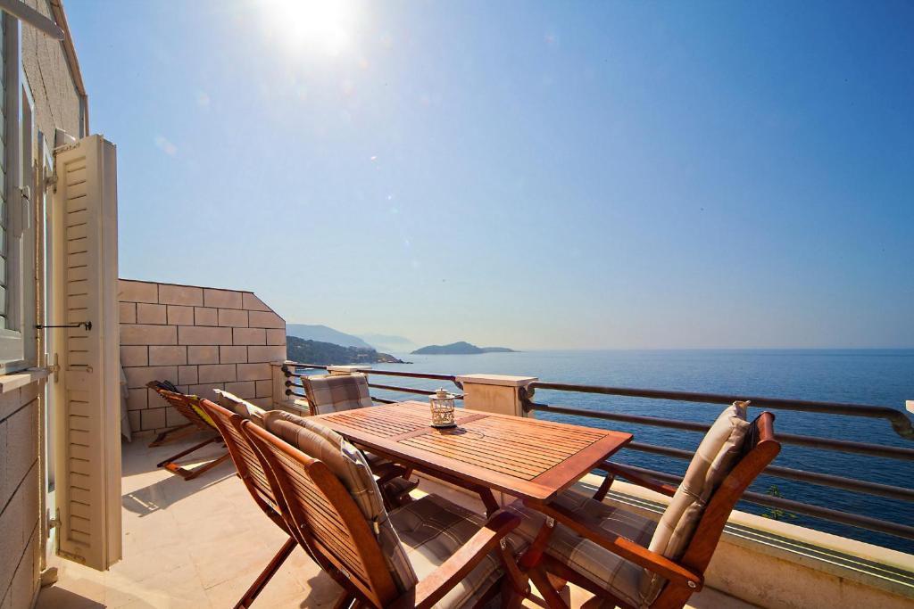 a wooden table and chairs on a balcony with the ocean at Big Blue Apartments in Dubrovnik