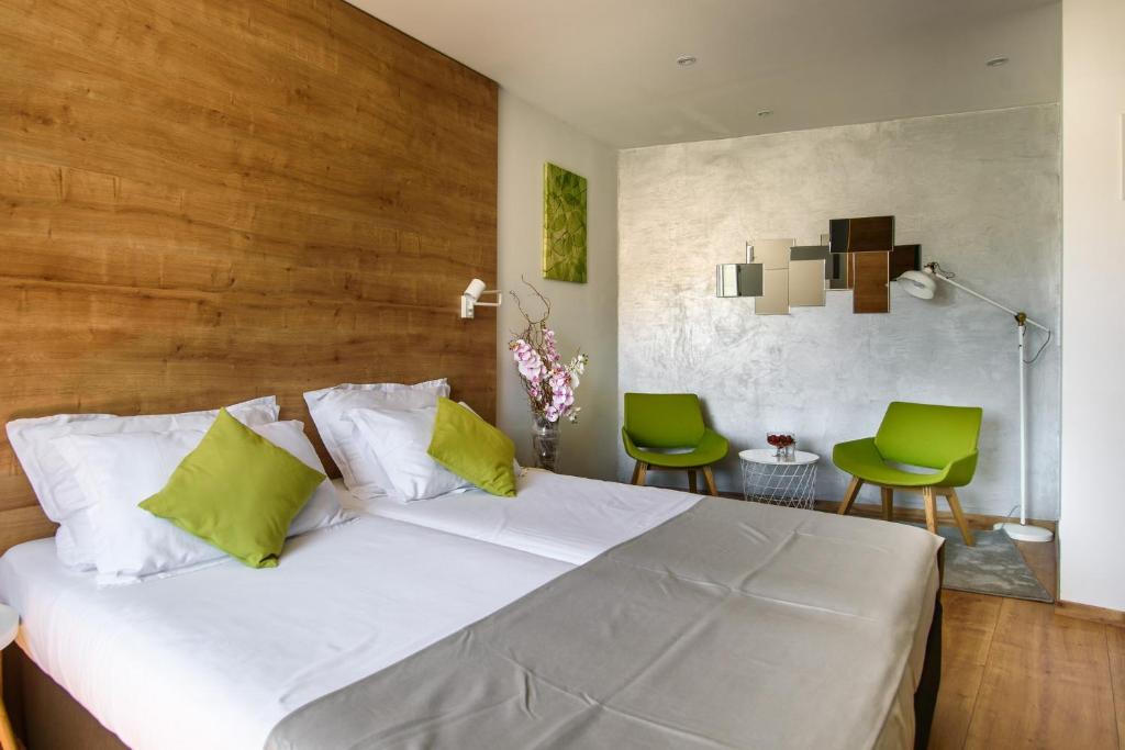 a bedroom with a white bed and two green chairs at Ora Luxury Rooms in Dubrovnik