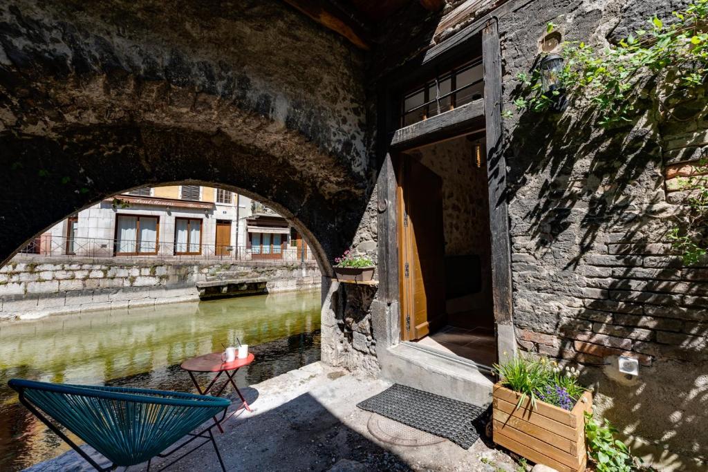 a building with an archway next to a river at La Maisonnette du Thiou - 50 square meters in the heart of Annecy in Annecy