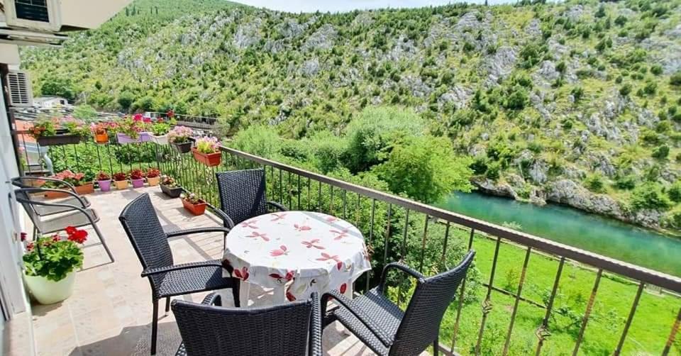 uma varanda com uma mesa e cadeiras e um rio em Villa Bašić em Blagaj