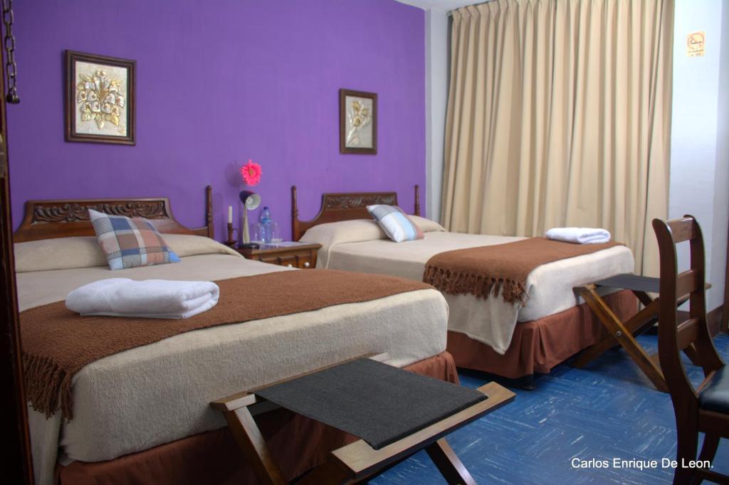 Habitación de hotel con 2 camas y paredes moradas en Hotel Doña Carmen, en Retalhuleu