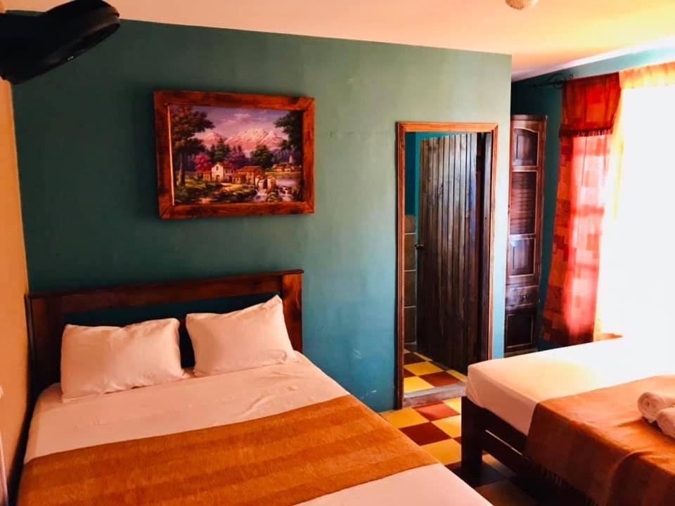 a bedroom with two beds and a painting on the wall at HOTEL EL ALMENDRO in Copan Ruinas