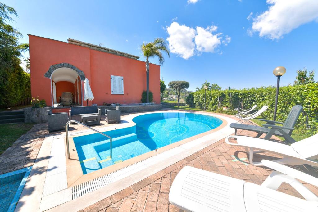 a swimming pool with chairs and a house at Villa Stefania in Ischia