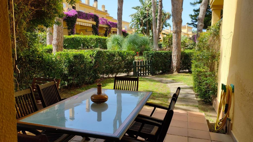 a glass table and chairs on a patio at Novo Sancti Petri Green del 11 in Chiclana de la Frontera