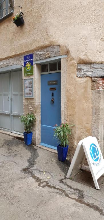 une porte bleue sur un bâtiment avec deux plantes en pot dans l'établissement La Porte Bleue, à Saint-Antonin