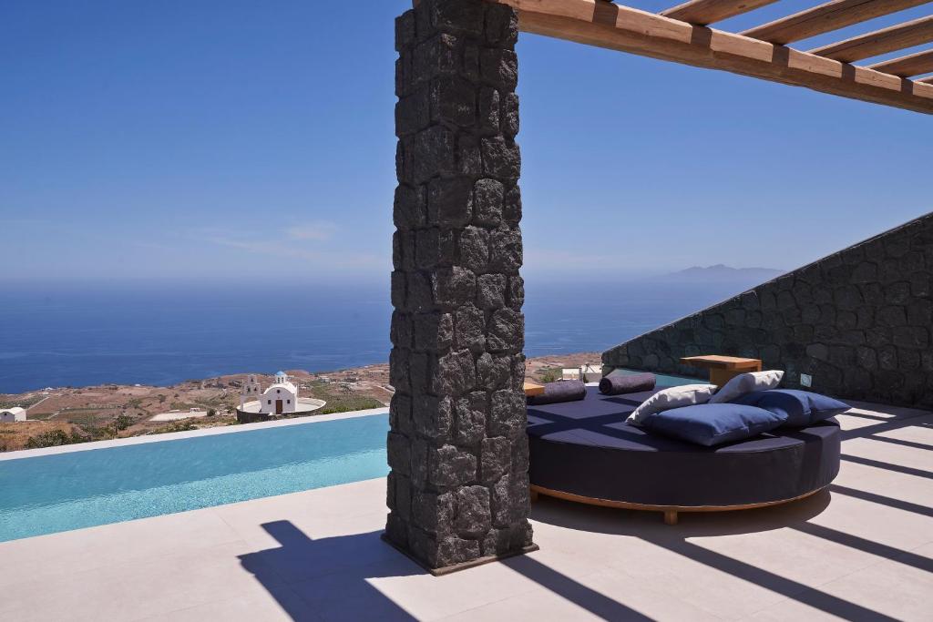 a room with a bed on a patio next to a pool at Brilliance Suites in Imerovigli