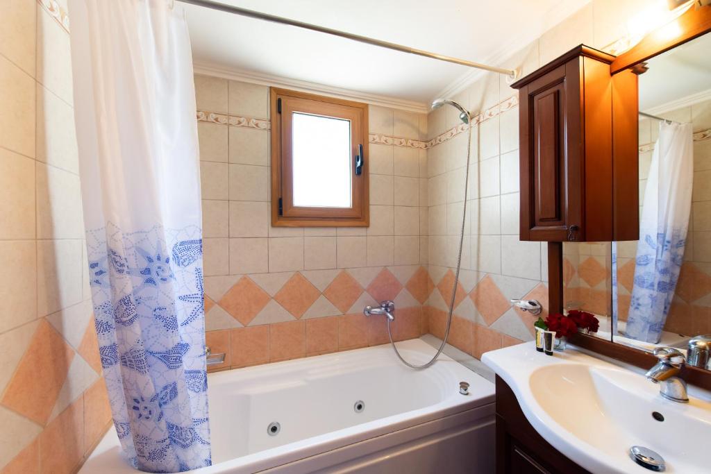 a bathroom with a tub and a sink and a bath tub at Delphinus Villa Nefeli in Agios Nikitas
