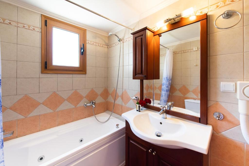 a bathroom with a sink and a tub and a mirror at Delphinus Villa Nefeli in Agios Nikitas