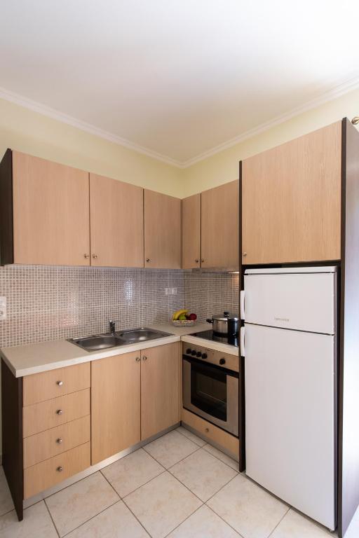 a kitchen with wooden cabinets and a white refrigerator at Delphinus Villa Nefeli in Agios Nikitas