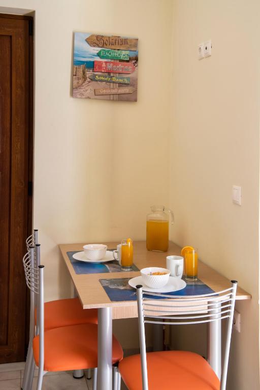 a small table with two chairs and a table with two cups of orange juice at Delphinus Villa Nefeli in Agios Nikitas