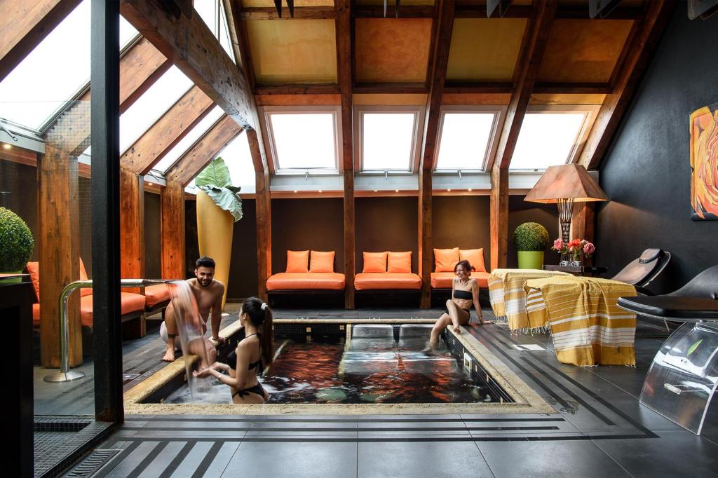 Un uomo e due ragazze seduti in una piscina in una stanza di Adua & Regina di Saba Wellness & Beauty a Montecatini Terme