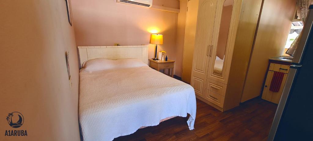 Dormitorio pequeño con cama blanca y lámpara en A1 Apartments Aruba en Oranjestad