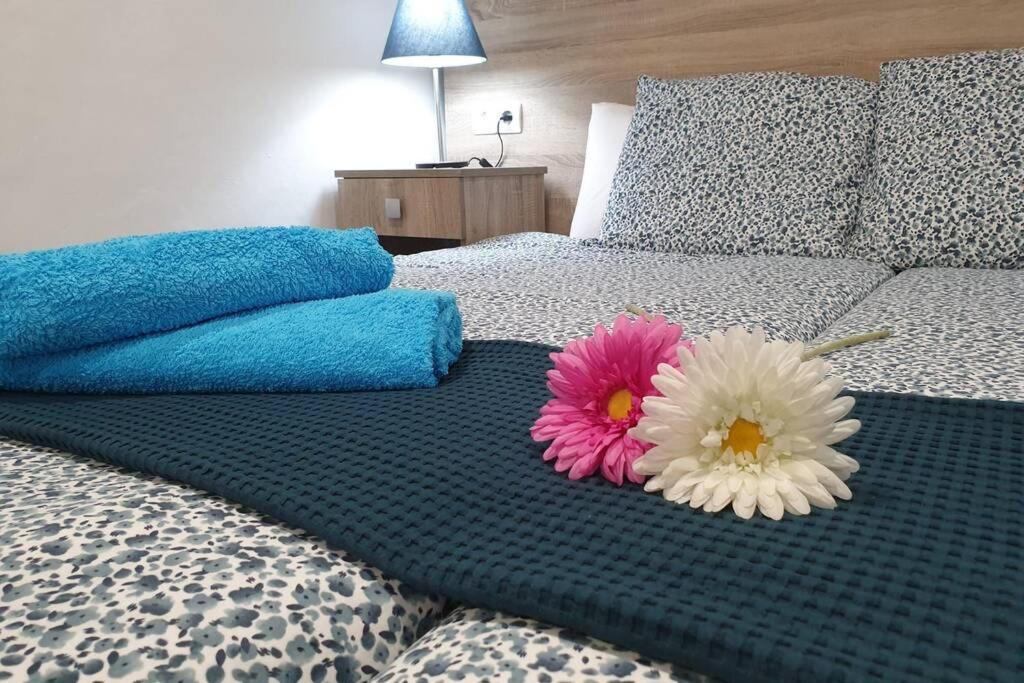 zwei Blumen auf einem Bett im Schlafzimmer in der Unterkunft Apartamento Eucalipto in Mozaga