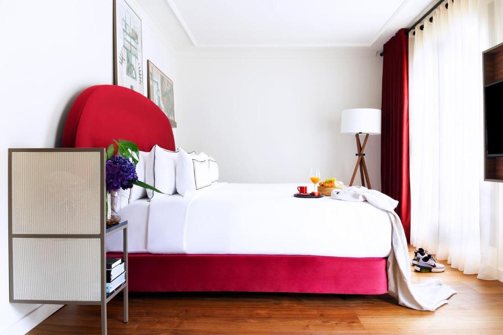 a bedroom with a white bed and a red chair at Villa Marquis Member of Meliá Collection in Paris