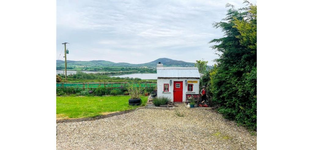 a small red and white house with a lake in the background at Lakeview House B&B in Baylet