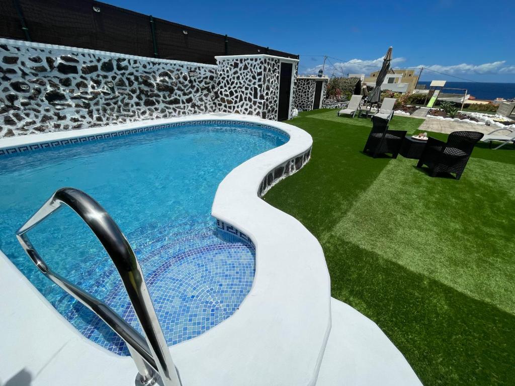 a swimming pool on a lawn next to a building at Vistamar La Caleta in La Caleta