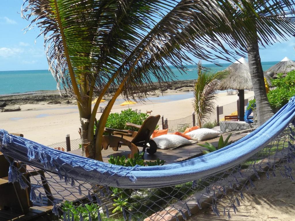 a hammock on a beach next to the ocean at Vila Bello Pontal in Coruripe