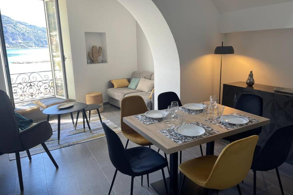 une salle à manger avec une table et des chaises et un salon dans l'établissement Menton 3 pièces vue mer bord de plage hyper centre, à Menton