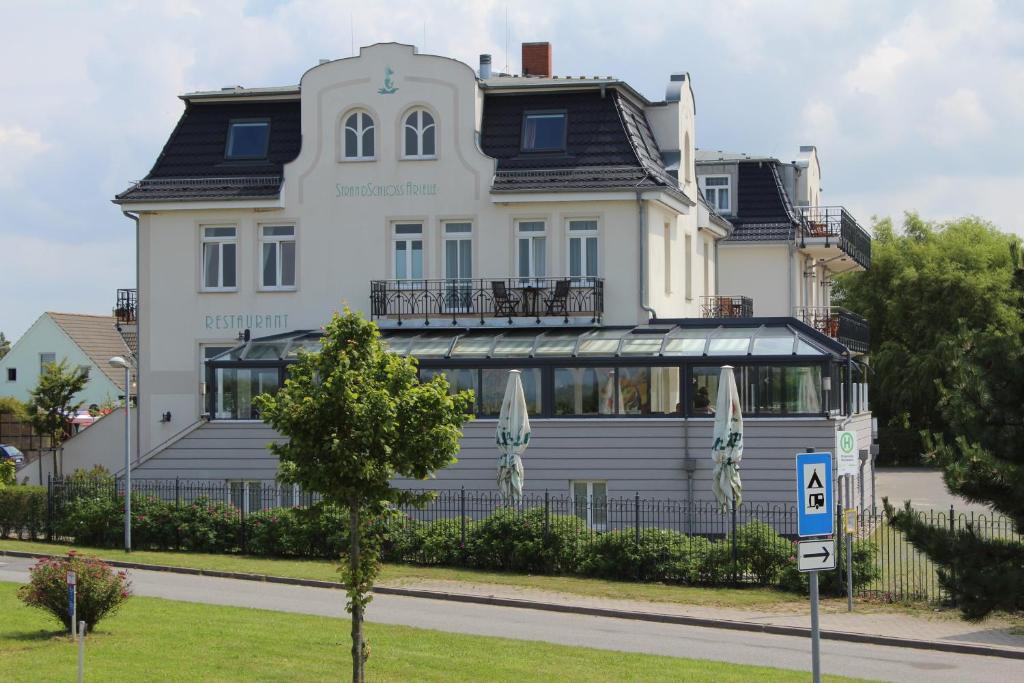 ein großes weißes Gebäude mit einem Schild davor in der Unterkunft Pension Strandschloss Arielle in Börgerende-Rethwisch