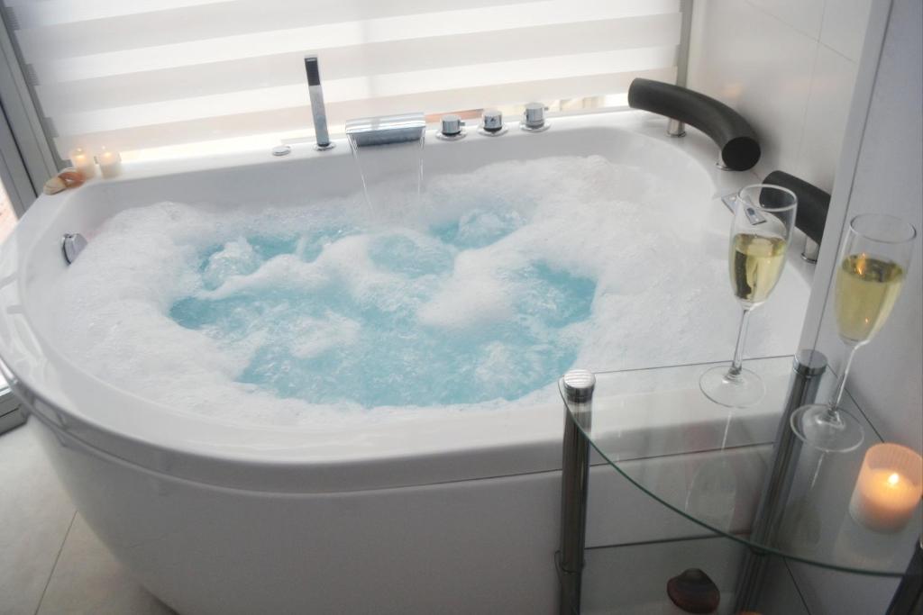 a bath tub filled with blue water with wine glasses at Blue Horizon Luxury Apartment in Nerja