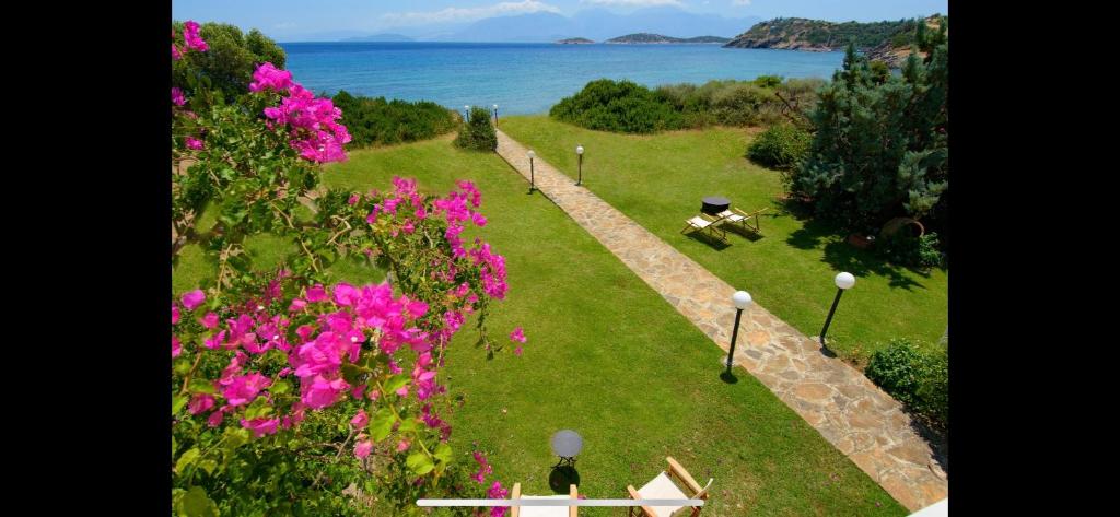 a garden with pink flowers and a view of the water at Mirabella Vista in Agios Nikolaos