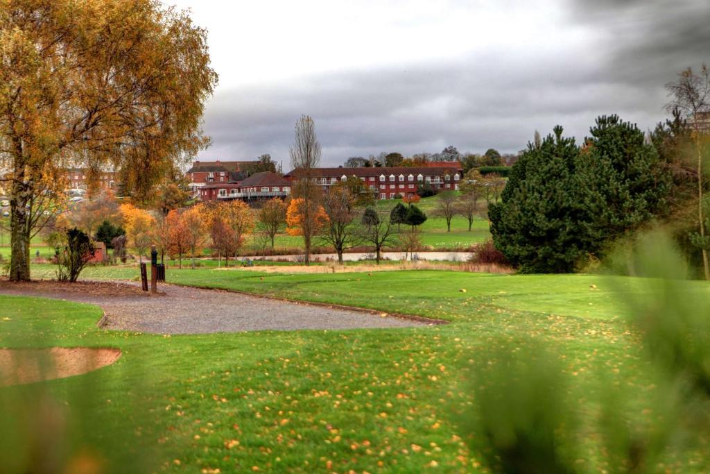 un parc avec des arbres et des bâtiments en arrière-plan dans l'établissement Windmill Village Hotel, Golf Club & Spa, BW Signature Collection, à Coventry