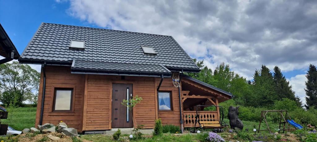 una pequeña casa de madera con techo negro en Czarny Potok, en Czarna