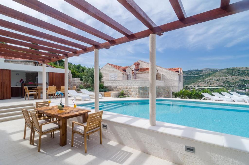 a patio with a table and chairs and a swimming pool at Modern Luxury Villa with Swimming Pool - Bayside View in Dubrovnik