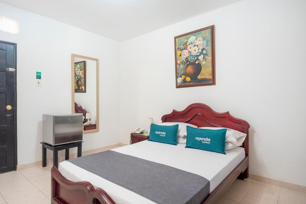 a bedroom with a bed with blue pillows and a tv at Ayenda 1309 Villa Dilia in Barranquilla