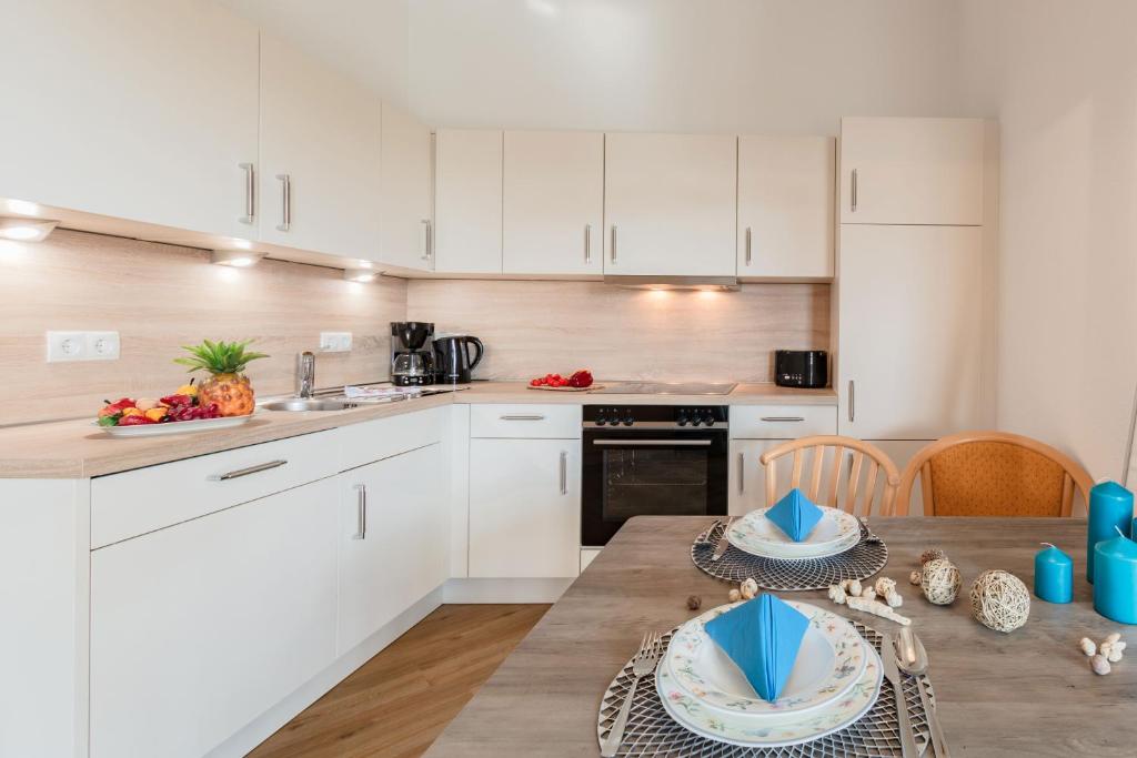 a kitchen with white cabinets and a wooden table at App Vilm mit Seeblick und schönem Balkon - tolle Ausstattung in Ostseebad Sellin