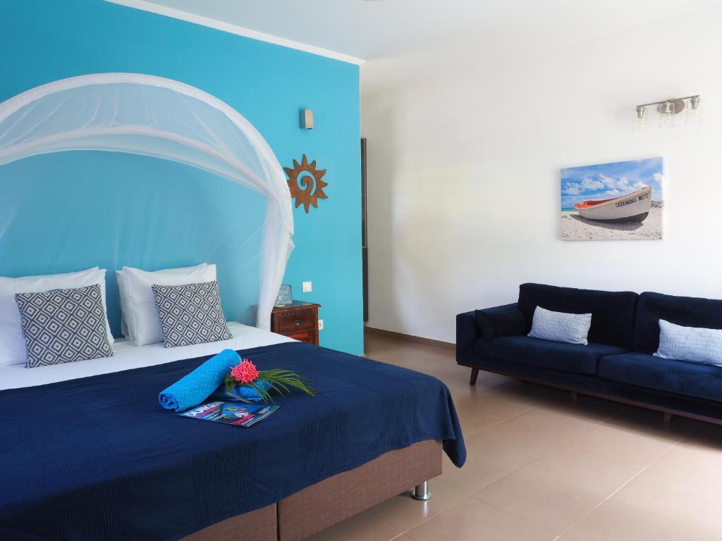 ChuChubi Studio Apartment Bonaire في كراليندايك: غرفة نوم بسرير واريكة