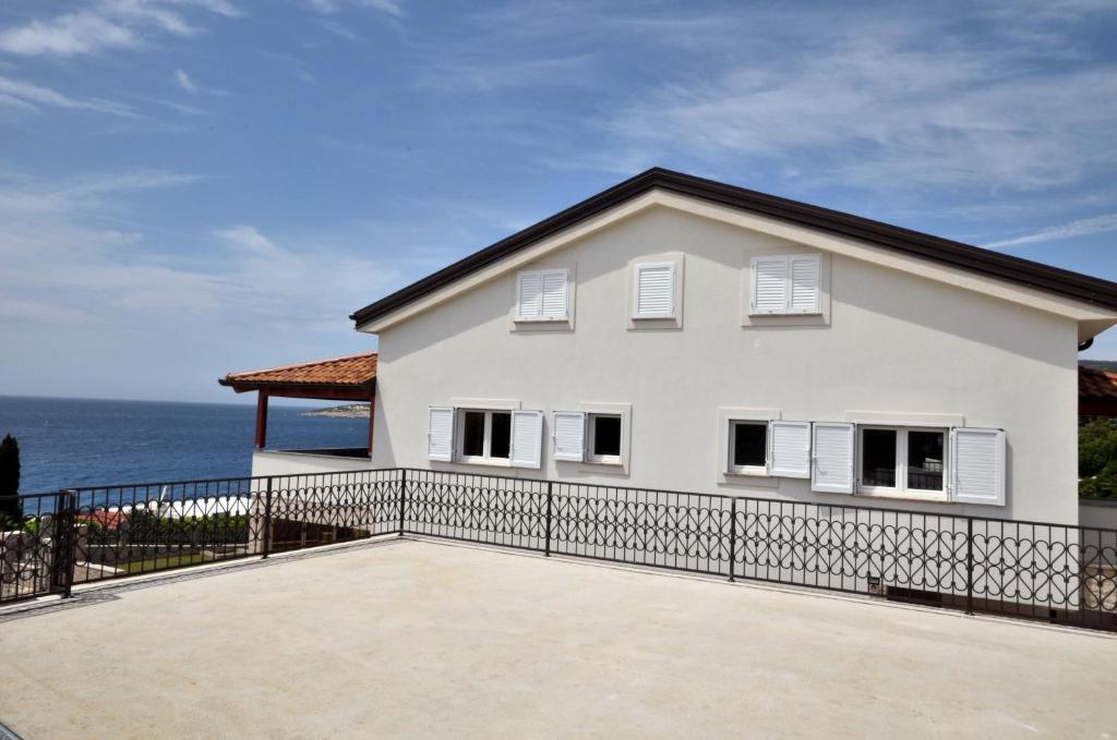 a white house with the ocean in the background at Apartments Villa Sofia in Martinšćica
