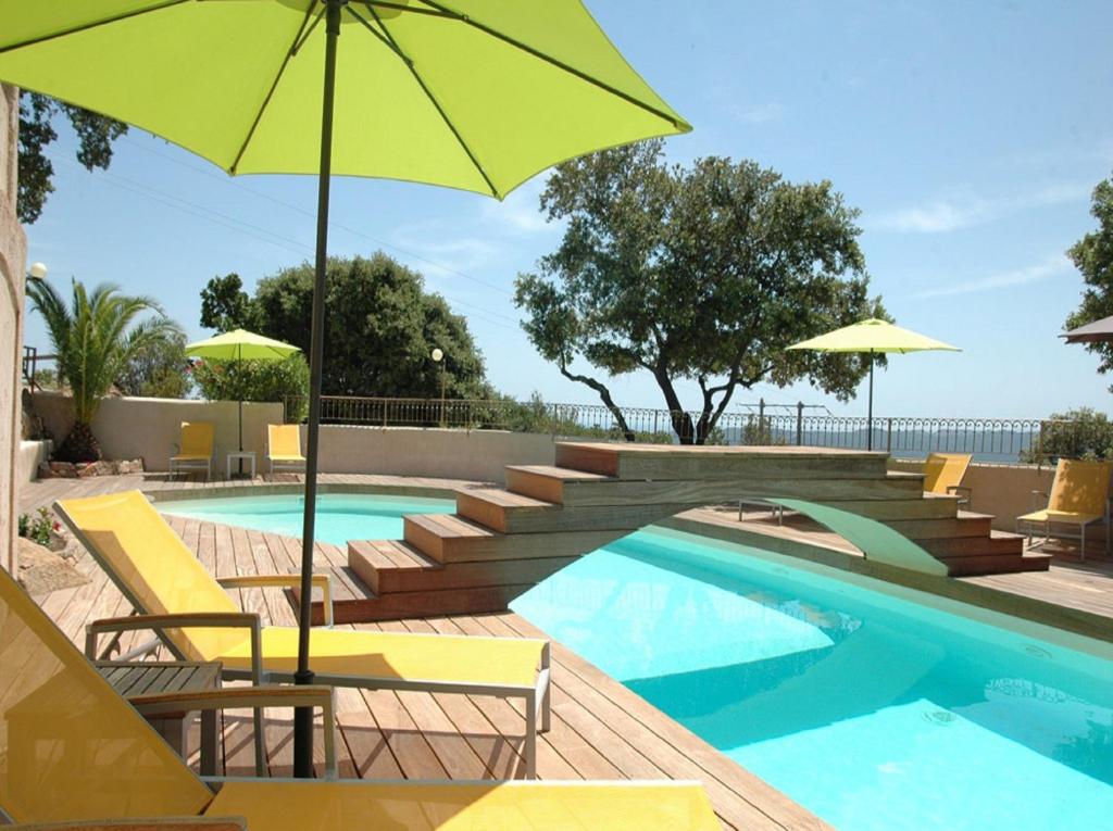 a swimming pool with yellow chairs and an umbrella at Bungalows Du Maquis in Porto-Vecchio