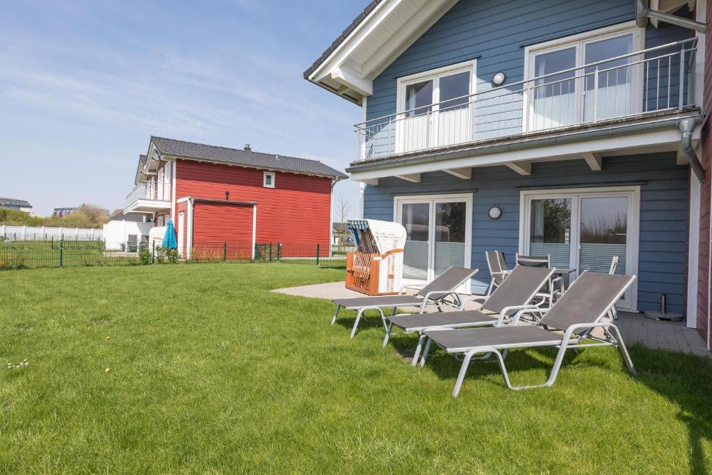 a group of lounge chairs on a lawn in front of a house at Ferienhaus Kampfläufer in Dagebüll