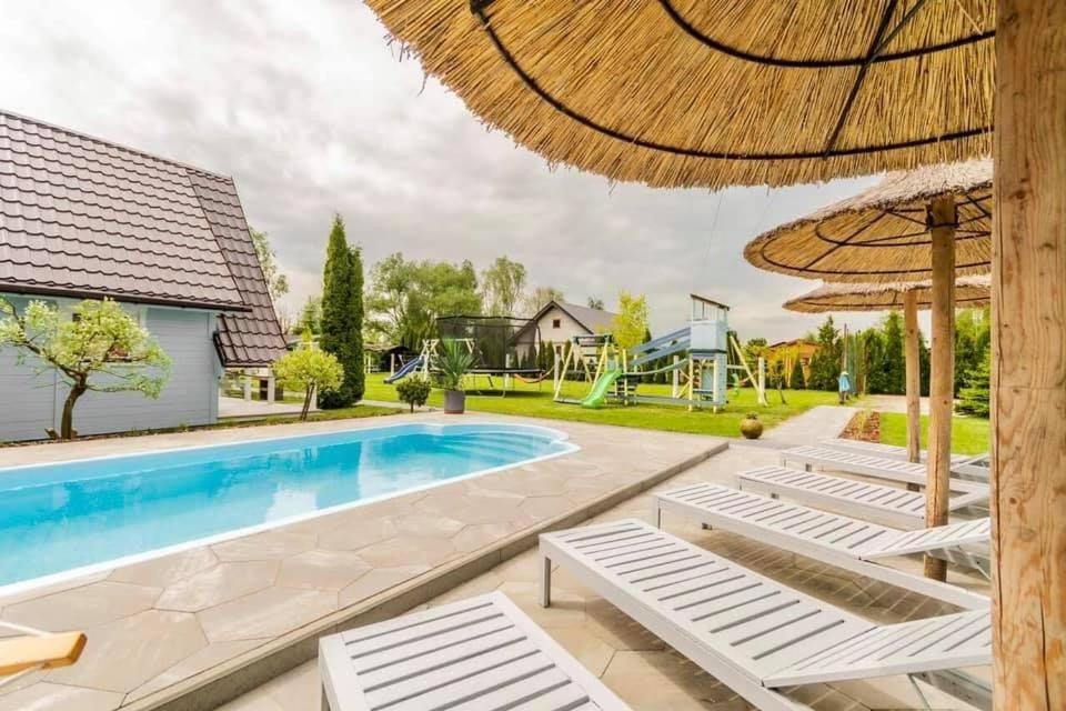 a swimming pool with chairs and an umbrella at Puszczykowo in Stegna