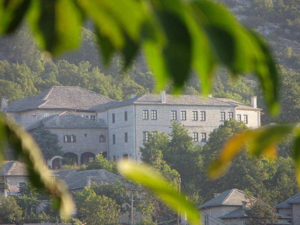 un grand bâtiment au sommet d'une colline plantée d'arbres dans l'établissement Hotel Monodendri, à Monodendri