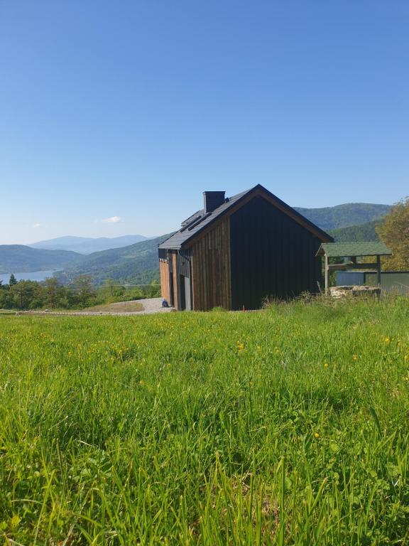 een zwart gebouw in een veld van groen gras bij Apartament Sielanka in Międzybrodzie Bialskie