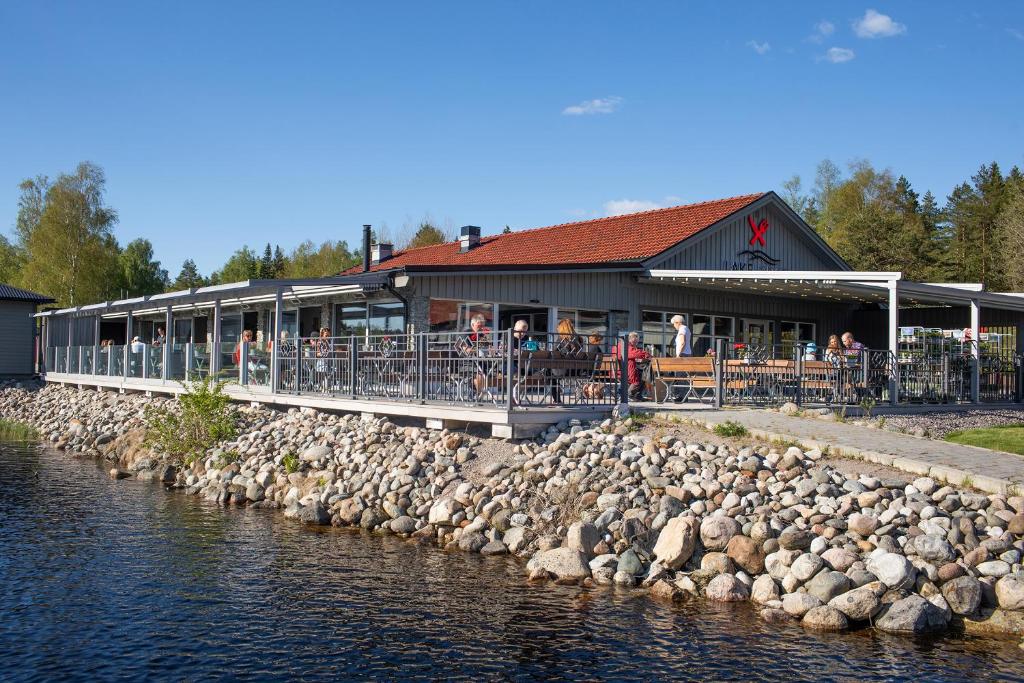 a building with a bunch of rocks next to a river at Lakelodge in Karlskoga
