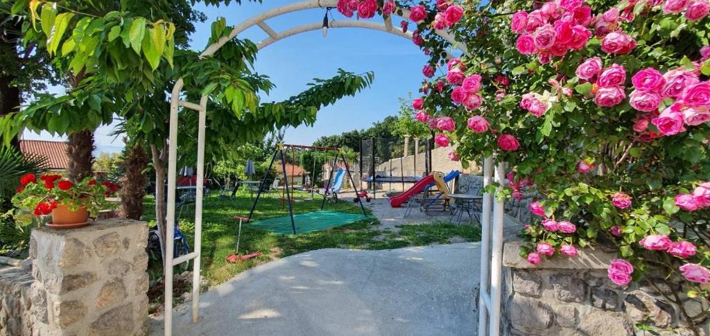 un jardín con un parque infantil con flores rosas en Villa Veronika, en Lovran